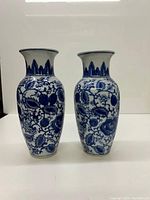 Pair of Chinese blue and white ceramic vases with floral and fruit pattern detail, standing side by side