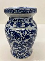 Front view of the miniature blue and white Chinese garden stool showing floral motifs and decorative bands on the neck and top rim.
