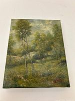 Front view of the signed landscape painting showing trees and sky with visible signature.