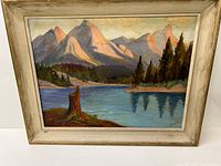 Framed landscape oil painting showing entire artwork with mountains, lake, tree stump, and pine trees.