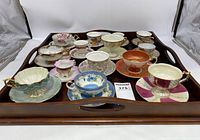 Tray of assorted collectible teacups and saucers showing variety of floral and ornate designs
