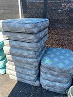 Stacks of gray outdoor seat and back cushions with woven pattern fabric, well-maintained condition.