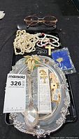 Overview of the lot items on tray including eyeglasses, necklaces, decorative tray, dice, pins, and letter opener.