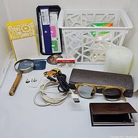 Full view of lot items showing sunglasses, office supplies, basket, magnifying glass, cables