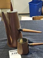 Large copper coffee pot with tapered shape, long spout, conical wooden lid knob, wooden handle, on black surface