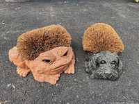 Photo showing the toad and dog outdoor boot scrapers side by side on asphalt.