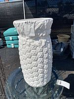 White ceramic umbrella stand shaped like a pineapple with textured body and leaf details around the top