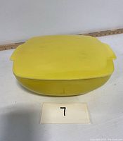 Top view of yellow square Pyrex bowl with lid, showing overall shape and color.