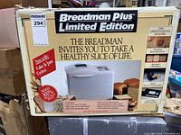 Box front view of Breadman Plus Limited Edition bread maker machine showing branding and features like loaf sizes, cake & jam cycles, and 3 hour delay timer, with original sealed packaging.