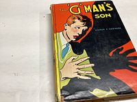 Front cover of 'The G Man's Son' showing illustrated young man and shadowy hand.