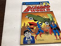 Photo of the comic book 'Tales of the Bizarro World' showing front cover with multiple Superman characters including a green car lifted above head.