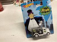 Front of unopened Hot Wheels 2014 Batman Penguin themed diecast vehicle in original packaging with character art and toy visible in clear blister.