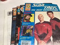Front view of five Star Trek magazines standing upright with colorful covers showing various characters including Captain Picard and Commander Riker.