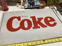 Front view of the metal sign showing prominently the red "Enjoy Coke" lettering on white.
