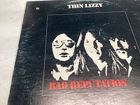 Front cover of Thin Lizzy 'Bad Reputation' vinyl record album showing band members and title on black background.