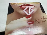 Front cover of the vinyl record album showing lips with red lipstick holding a TS logo stick and the album title 'Love Is For Suckers'.