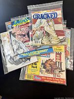 Photos showing vintage comic books in plastic sleeves, featuring titles Cracked, Wonder Woman, and others.