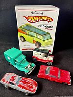 Warman's Hot Wheels Field Guide 4th Edition book with four vintage Dinky toy cars displayed in front of it.