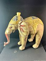 Front-side view of the carved wooden elephant showing intricate painting and size comparison with a quarter coin.