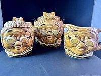 Photo showing all three Mrs. Ben Franklin pieces: teapot, sugar bowl, and creamer pitcher with the character face design.