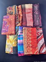 Overview of 10 ladies scarves showing various prints and colors including floral, paisley, abstract, and striped designs.