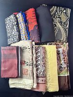 All 11 scarves neatly folded displaying various patterns and colors including geometric, floral, and paisley prints.