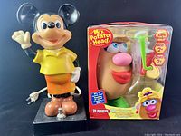 Front view showing Mickey Mouse bobble head lamp standing on black base next to unopened Mrs Potato Head toy box.
