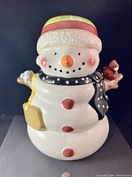 Full view of the snowman cookie jar showing facial details, hat, scarf and arm holding red cardinal