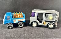 Side-by-side view of the Pepsi-Cola truck and the armoured car coin bank showing the truck bed with orange bottles and the coin slot in the armoured car.