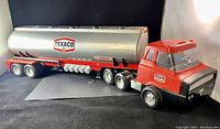 Side view of full tanker truck showing red and silver colors, Texaco logo, and tanker detailing.