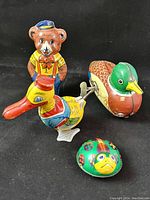 Group photo showing four vintage tin litho wind-up toys including bear, duck, ladybug, and mallard.