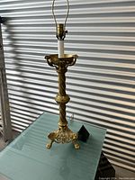 Full view of one brass candlestick lamp showing base, column, harp, and wiring