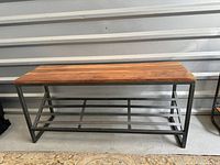 Front view of bench showing wood top, metal frame and slatted shoe shelf
