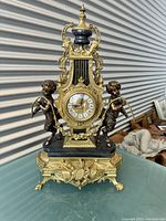 Three-quarter front view of entire clock showing gilt bronze case, black marble platform and cherub figures