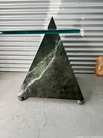 Side view of green patina metal pyramid base showing one spherical foot.