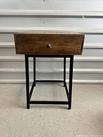 Front view of one wood and metal night stand showing the drawer and metal legs
