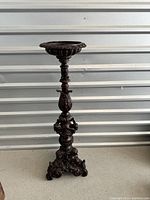 Full view of bronze pedestal planter showing lobed bowl and tripod base