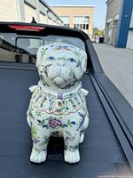 Front angle view of one porcelain dog figurine showing detailed floral and butterfly hand-painted designs on face and collar.