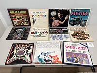 Photo of 11 vinyl records front covers depicting blues, jazz, disco, swing, and rock genres with varied colorful artwork.