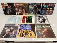 Full view of front covers of 10 vinyl records from various artists placed on a table.