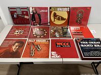 Top view of vinyl record covers laid out on table showing 12 different albums by various artists including Eagles, Tom Petty, Ventures, Toto, Billy Vaughn, WCCC