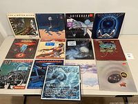 Photo showing fronts of 12 vinyl album covers including major rock bands and artists such as The J. Geils Band, Boston, Journey, and others.