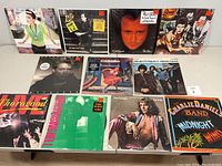 Front view of 12 vinyl record album covers laid in two rows, titles visible including Madonna Like A Virgin and Billy Joel An Innocent Man, plus others.
