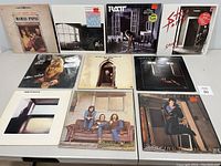 Full front view of all 10 vinyl albums arranged in two rows on table showing front covers.