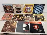 Full set of 12 vinyl records shown upright with colorful album covers from various rock and classic artists including Beatles, Stones, Hendrix, The Who among others.