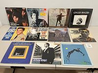 Front view of 11 vinyl records with covers displayed on table.
