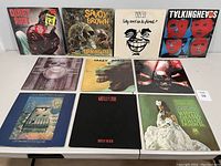 Front cover of eleven vintage vinyl albums laid out on table, upright and face forward.