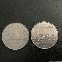 Obverse sides of 1975 and 1982 Canadian dollar coins showing canoe scene and Confederation Constitution respectively.