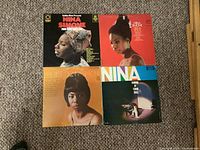 Photo showing four Nina Simone LP records laid on carpet: 'Fine & Mellow', 'Silk & Soul', 'Best of Nina Simone', and 'Simone at Town Hall'. LP covers show Nina Simone portraits and have varying background colors.