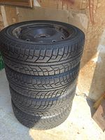 Stack of four mounted snow tires showing tread pattern and overall condition
